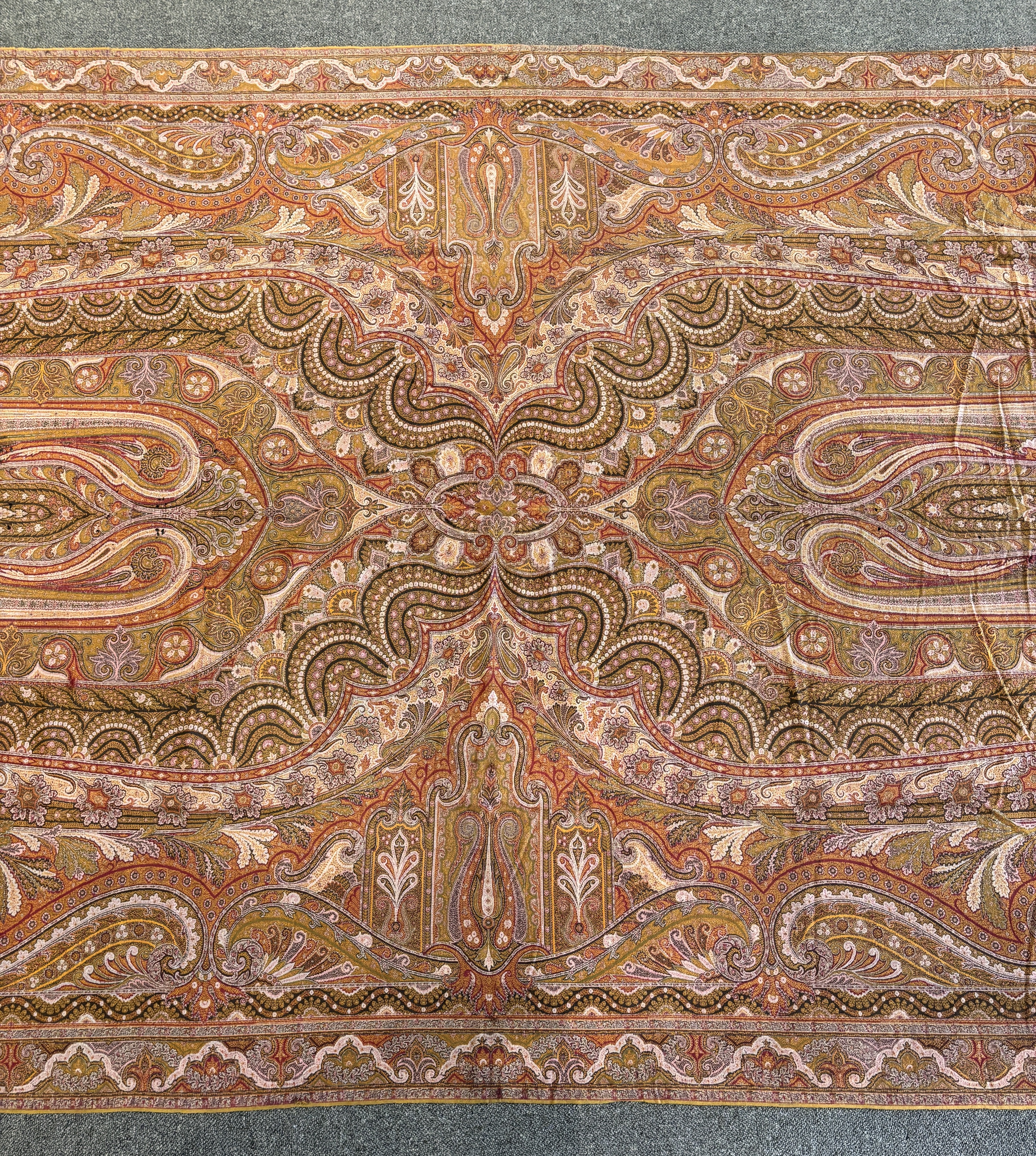 A 19th century woven Scottish Paisley wool shawl, bordered on four sides and fringed on two, woven with two ornate teardrop designs and a central cartouche, 334cm long x 160cm wide